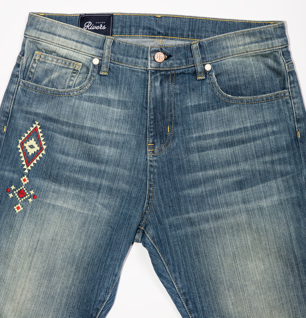 United Rivers Kansas River medium wash denim jeans with five-pocket with zipper fly and signature snap rivets and “UR” label at the main button